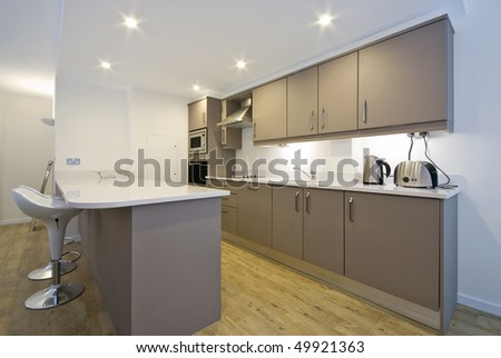 Modern fully fitted kitchen with appliances and bar seating in white