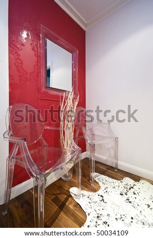 Detail of a modern entrance hall with designer transparent chairs and processed cow fur
