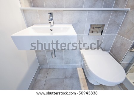 Detail of a modern en suite bathroom with ceramic toilet, wash basin in beige