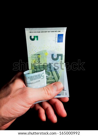 Old and new five Euro bills held by a male towards black background