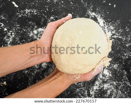 Person holding a proof dough over black table with flour mess