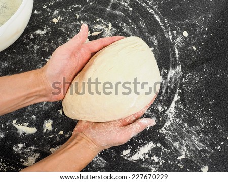 Person holding a proof dough over black table with flour mess