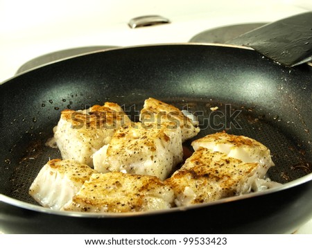 Someone frying seasoned white fish in a frying pan