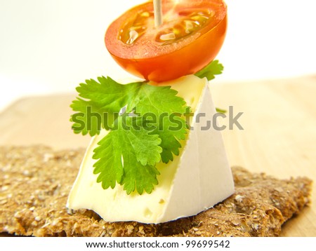 Cracker on wooden board, with soft cheese and tomato