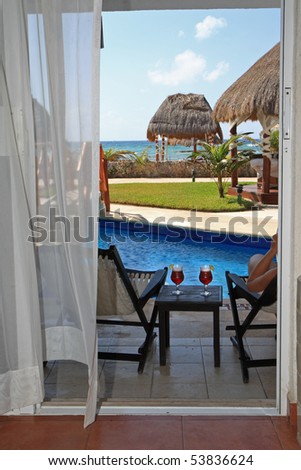 looking out through open door to drinks, pool, tropical grounds