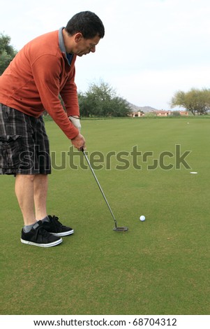 middle-aged man about to make a golf putt