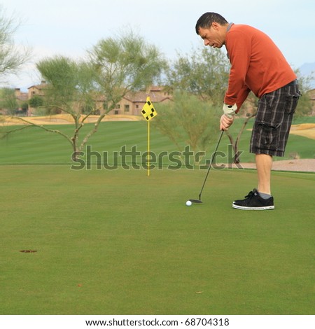 middle-aged man practicing his golf putts