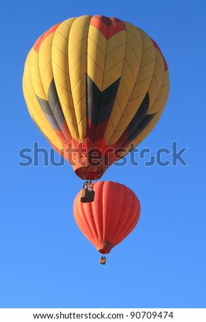 two hot air balloons rise into clear blue sky