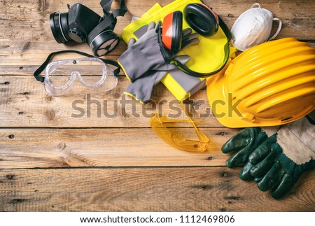 Construction site safety. Protective hard hat, headphones, gloves, glasses and masks on wooden background, copy space, top view