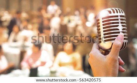 Wedding meeting and event on stage concept - Close up retro microphone in singer hand on stage of business meeting or event whit flare light effect and copyspace