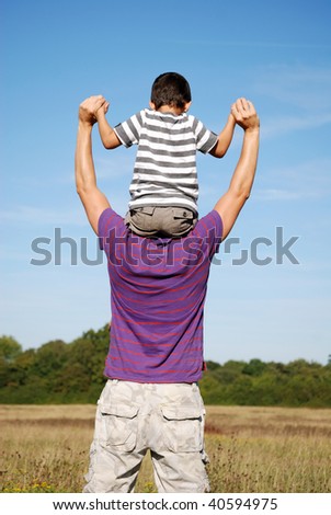 Young boy carefully holding on to his dads hands while on shoulders