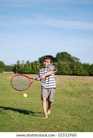 Young boy playing tennis outside