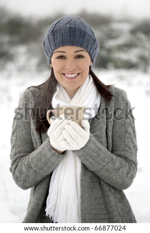 Woman smiling holding hot drink outside in the snow