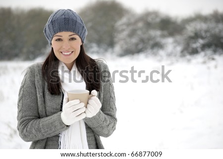 Woman smiling holding hot drink outside in the snow