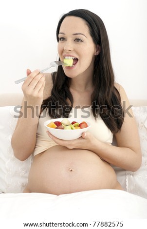 Pregnant woman eating breakfast in bed