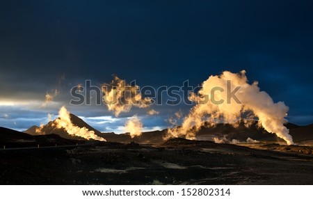 Steam erupting from geothermal power station at sunset, yellow light of setting sun back-lighting the columns of steam, Myvatn area, Iceland