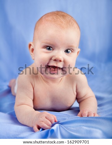 Blue eyed smiling baby girl on her stomach