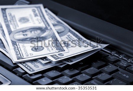 American dollars laying on laptop toned blue