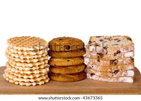 Piles of wafers, oatmeal biscuits and cake on wooden board, isolated