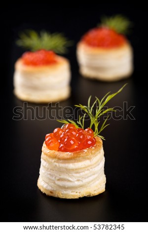 Tartlets with red caviar on black background