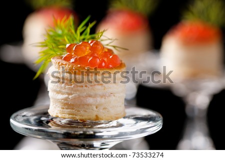 Tartlets with red caviar on black background