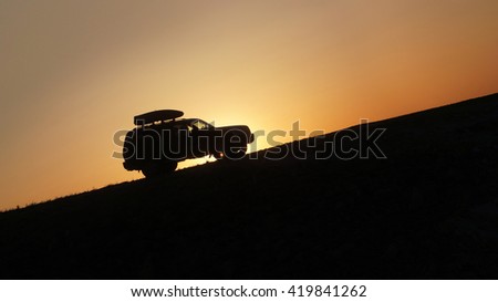 The car on a background of sunset rides on top of the mountain