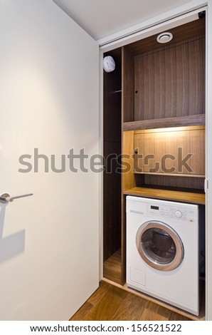 open door on a utility room with wooden shelving and washing machine