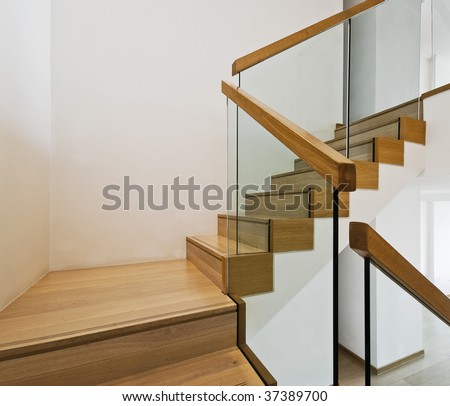 contemporary stair case with wooden steps and glass rails