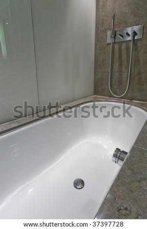 large luxury bath with shower attachment and marble tiles