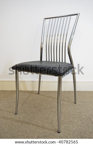 isolated contemporary chair with metal frame and leather cushioned seat