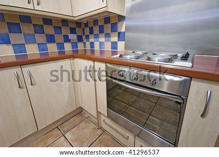 kitchen with wooden worktop and checked yellow and blue ceramic tiles
