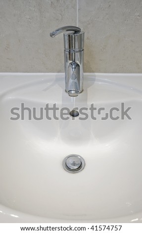 detail of a white ceramic hand wash basin with chrome water mixer tap over