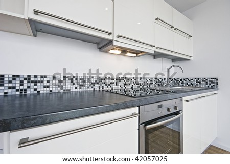 modern white kitchen with stone worktop and mosaic tiles