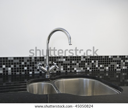 detail of a stainless steel kitchen sink on a black granite worktop
