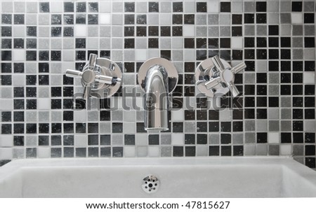 modern designer chrome water mixer tap on  mosaic tile wall