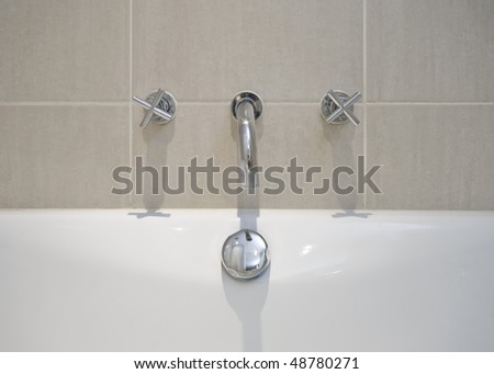 detail of a modern designer water mixer tap over bath tub