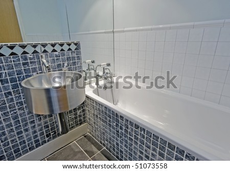 bathroom detail with stone tiles and stainless steel sink