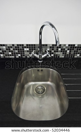 kitchen sink detail with a back granite worktop and designer water tap