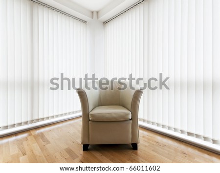 beige leather armchair in a room with wooden floor and vertical blinds