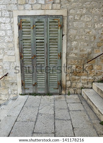 Old green shutter door between stairs in old town Sibenik, Croatia