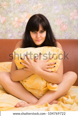 Sexual young woman in a bed with pillow. Selective focus on eyes.