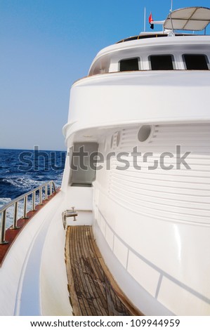 Deck of big wooden marine yacht with portholes and deck cabin in the sea.