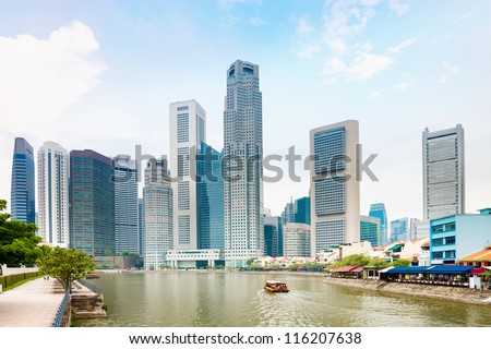 Singapore quay with tall skyscrapers in the central business district and and small restaurants on Boat Quay