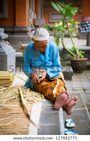 TAMPAK SIRING, BALI, INDONESIA - SEP 21: Old woman make baskets for balinese traditional offerings to gods in temple Puru Tirtha Empul on Sep 21, 2012 in Tampak Siring, Bali, Indonesia