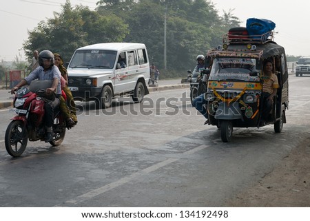 AGRA, INDIA - NOVEMBER 15: Overloaded motorcycles, cars and tuk-tuks drive on covered by haze Ring road (Delhi - Agra) on Nov 15, 2012 in Agra, India