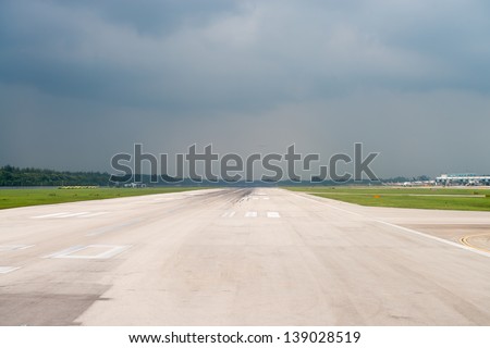 Wide airport runway under dark cloudy storm sky