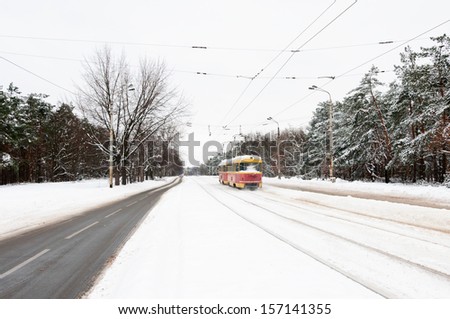 Red and yellow tram on a snow winter road near a park, Kyiv, Ukraine