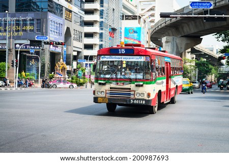 BANGKOK, THAILAND - 21 NOV 2013: Public transport bus passes crossroads street with skytrain track on background