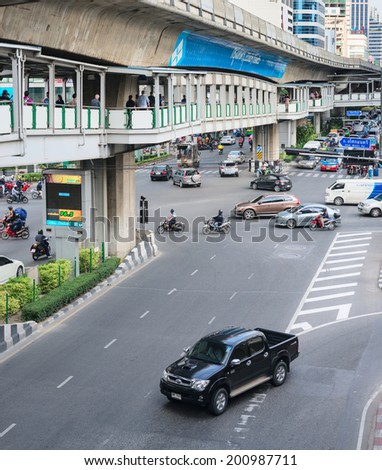 BANGKOK, THAILAND - 21 NOV 2013: Motorbikes and cars traffic move on road with pedestrian and skytrain tracks above street