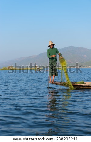 INLE LAKE, MYANMAR (BURMA) - 07 JAN 2014: Burmesel fisherman in wooden boat leg row and use net to catch fish in Inle lake, Myanmar